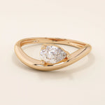 Pear cut moissanite solitaire engagement ring on a curved 14k solid gold band, minimalist design with a modern twist.