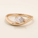 Pear cut moissanite solitaire engagement ring on a curved 14k solid gold band, minimalist design with a modern twist.
