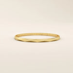 Side angle of a 14k solid yellow gold faceted bangle bracelet, highlighting its sleek, angled planes and smooth, high-polish finish.
