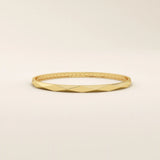 Side angle of a 14k solid yellow gold faceted bangle bracelet, highlighting its sleek, angled planes and smooth, high-polish finish.
