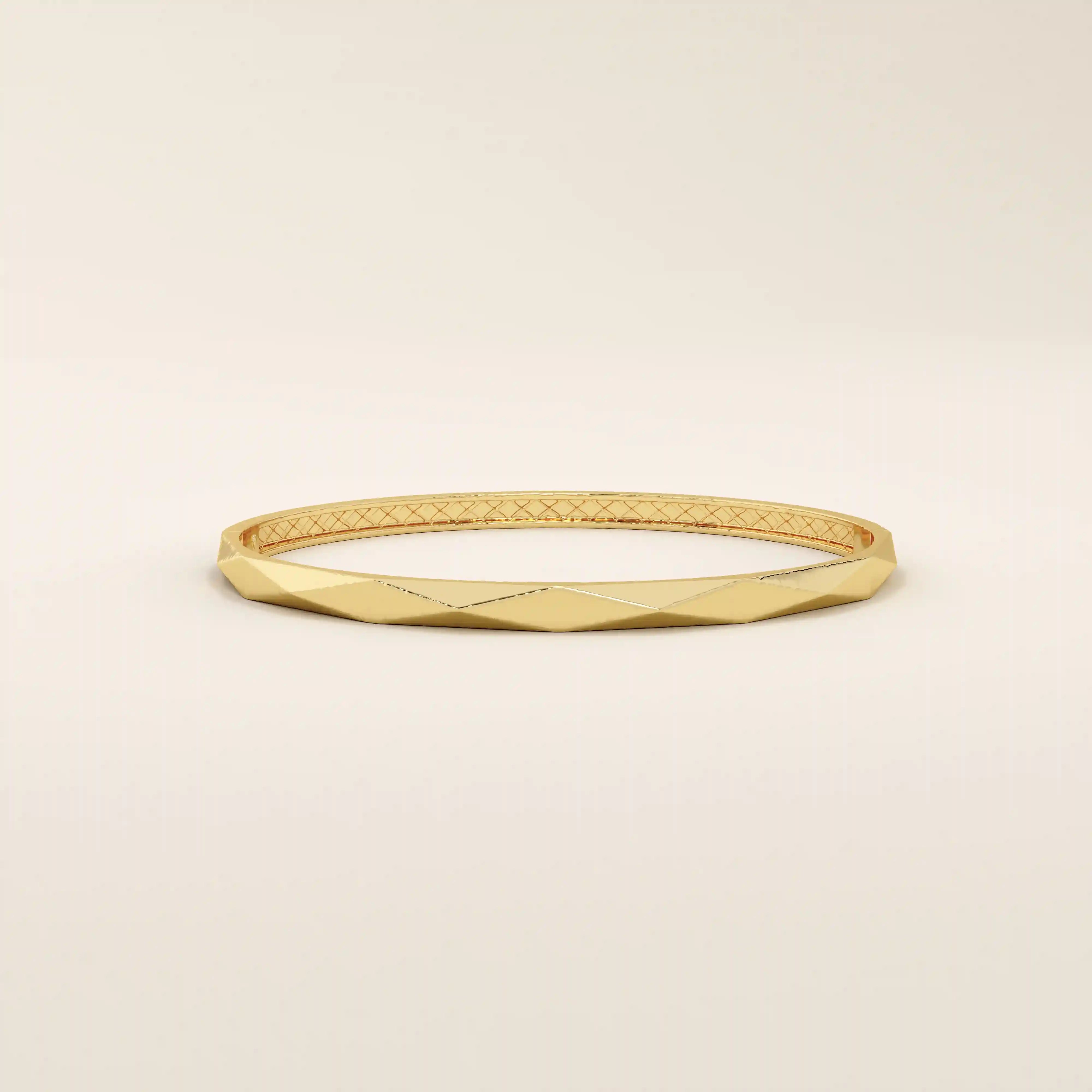 Side angle of a 14k solid yellow gold faceted bangle bracelet, highlighting its sleek, angled planes and smooth, high-polish finish.
