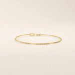 Side angle of a 14k solid yellow gold flat bar chain bracelet, showing the slim rectangular links and the light-catching polished finish.
