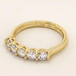 Side angle view of a 14k solid yellow gold band with five round brilliant cut moissanite stones in a prong setting and engraved shank detail, classic and elegant bridal jewelry
