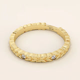 Side angle view of a 14k solid yellow gold band with laurel leaf design and bezel set round brilliant cut moissanite stones, refined and unique bridal jewelry
