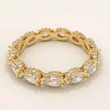 Side angle view of a 14k solid yellow gold eternity band with sideways pear cut moissanite stones and pavé set round moissanite accents, finished with detailed milgrain edges for an opulent bridal look

