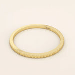 Side angle view of a 14k solid yellow gold thin stacking ring with faceted textured design, simple and modern fine jewelry for layering
