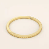 Side angle view of a 14k solid yellow gold thin stacking ring with faceted textured design, simple and modern fine jewelry for layering
