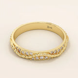 Side angle view of a 14k solid yellow gold twisted eternity wedding band with moissanites set in an interwoven design

