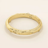 Side angle view of a 14k solid yellow gold wedding band with woodgrain-inspired detailing, nature-inspired craftsmanship
