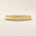 Side view of a 14k solid yellow gold twisted rope bangle showcasing its dimensional braided design, smooth contours, and lustrous finish.
