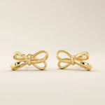 Simple ribbon stud earrings in 14k yellow gold with a polished bow design.
