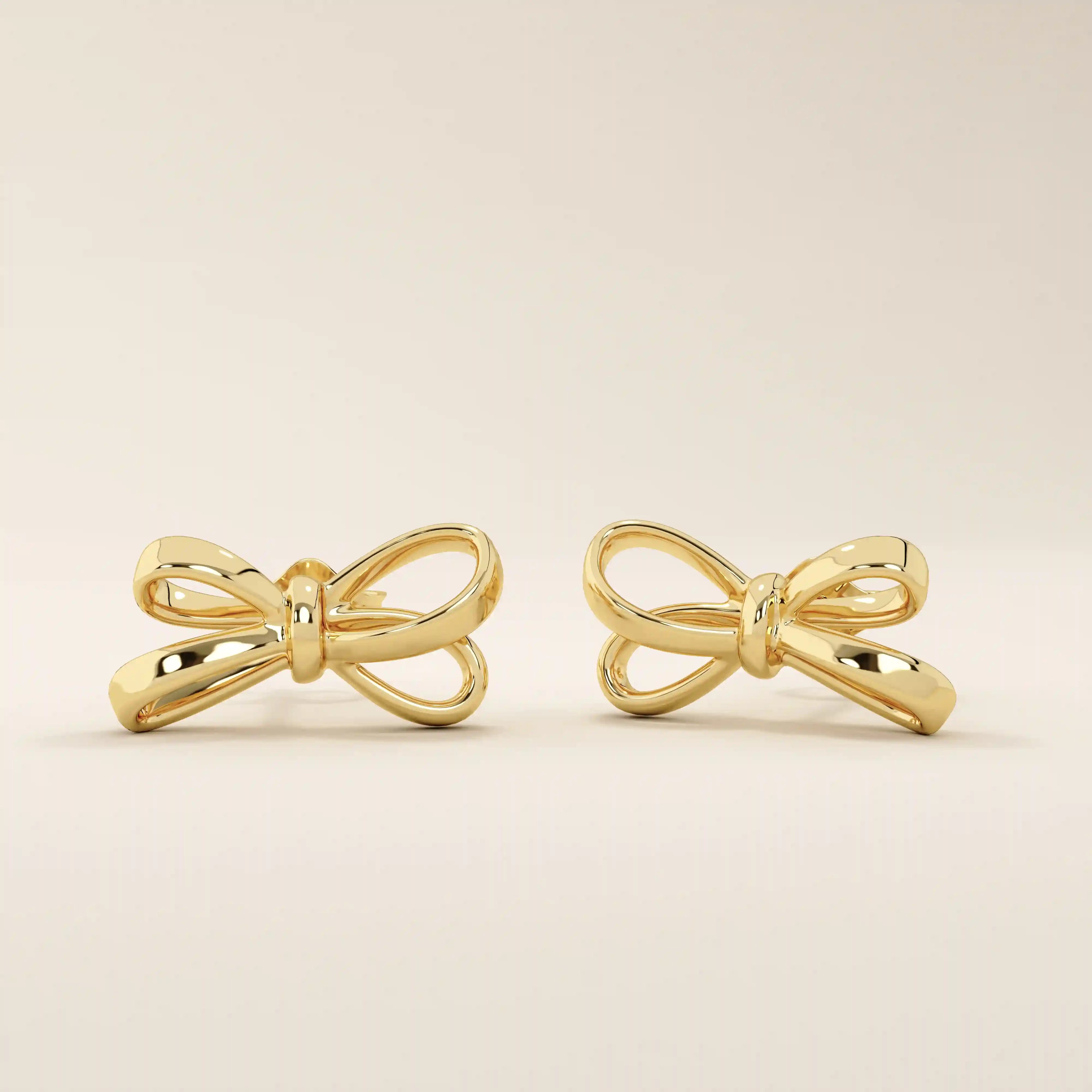 Simple ribbon stud earrings in 14k yellow gold with a polished bow design.
