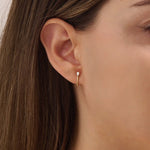 Woman wearing 14k solid gold U-shaped stud earrings with pear moissanites at the front. Bold yet minimal gold studs for everyday style. Great for adding a touch of sparkle.