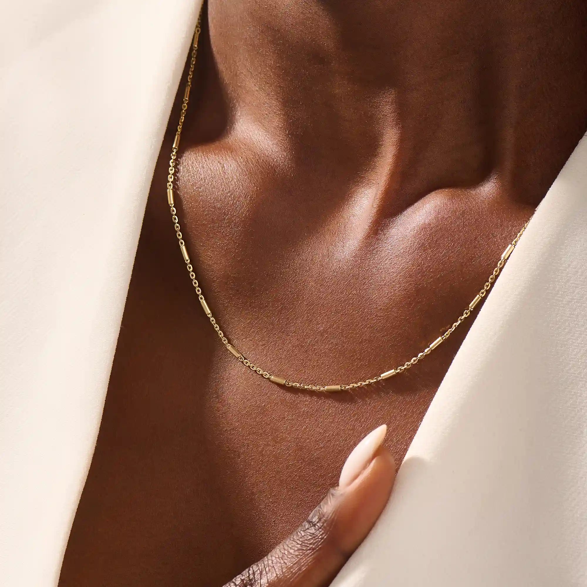 Woman wearing a 14k solid gold bar chain necklace with clean, linear links. A contemporary and elegant gold piece. Perfect for daily wear or stacking.