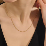 Woman wearing a 14k solid gold bar chain necklace with clean, linear links. A contemporary and elegant gold piece. Perfect for daily wear or stacking.