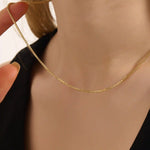 Woman wearing a 14k solid gold box chain necklace with sleek, structured links. Minimalist and versatile gold chain for everyday styling. Perfect on its own or with other pieces.