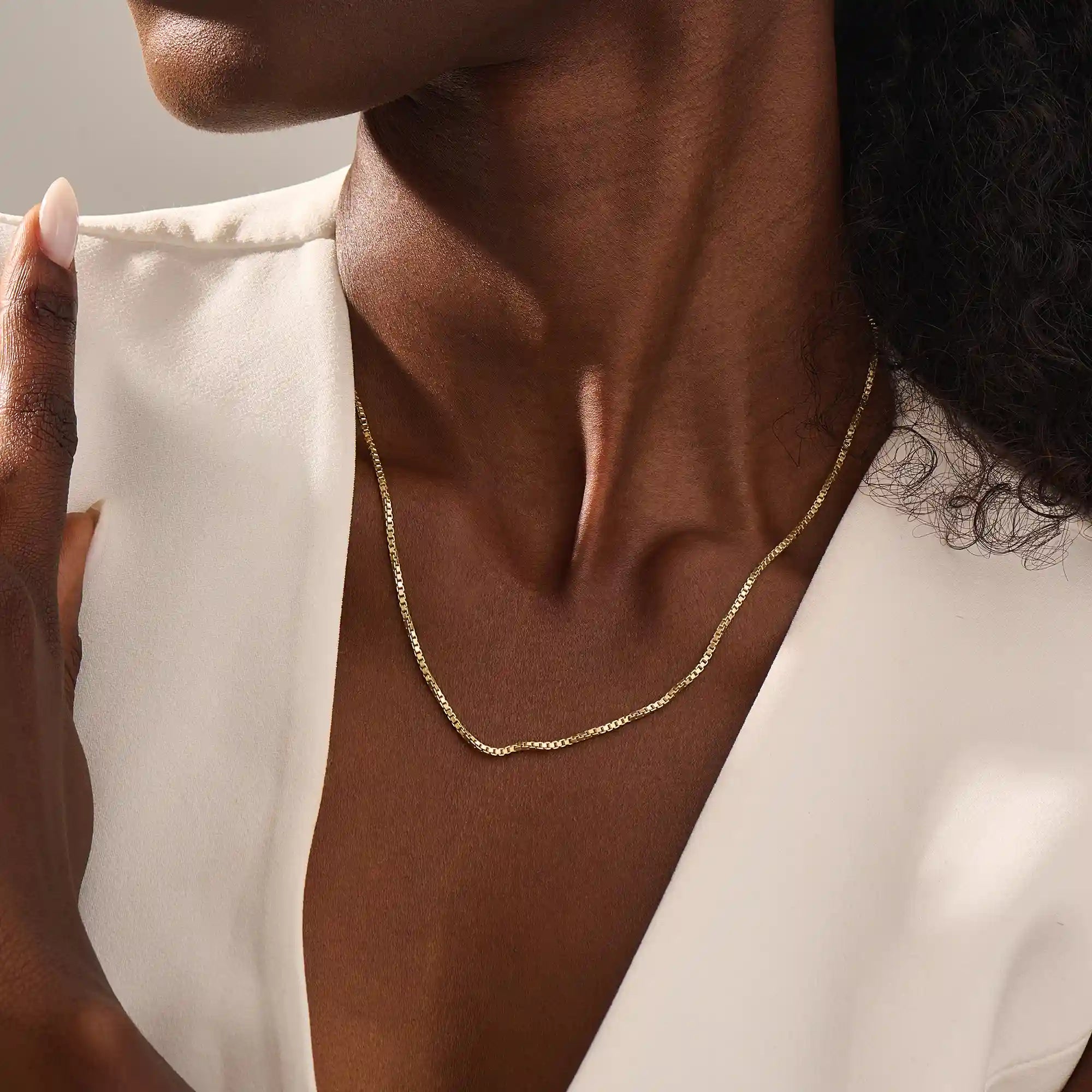 Woman wearing a 14k solid gold box chain necklace with sleek, structured links. Minimalist and versatile gold chain for everyday styling. Perfect on its own or with other pieces.