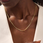 Woman wearing a 14k solid gold curb chain necklace with smooth, flat links that catch the light. A bold yet classic piece for daily styling. Perfect worn solo or stacked.