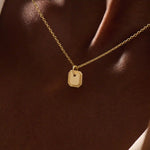 Woman wearing a 14k solid gold dainty octagon pendant necklace. Lightweight and easy-to-style gold charm. Perfect for daily looks or as a layering piece.