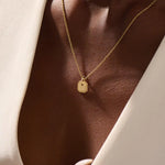 Woman wearing a 14k solid gold dainty octagon pendant necklace. Lightweight and easy-to-style gold charm. Perfect for daily looks or as a layering piece.