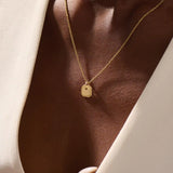 Woman wearing a 14k solid gold dainty octagon pendant necklace. Lightweight and easy-to-style gold charm. Perfect for daily looks or as a layering piece.