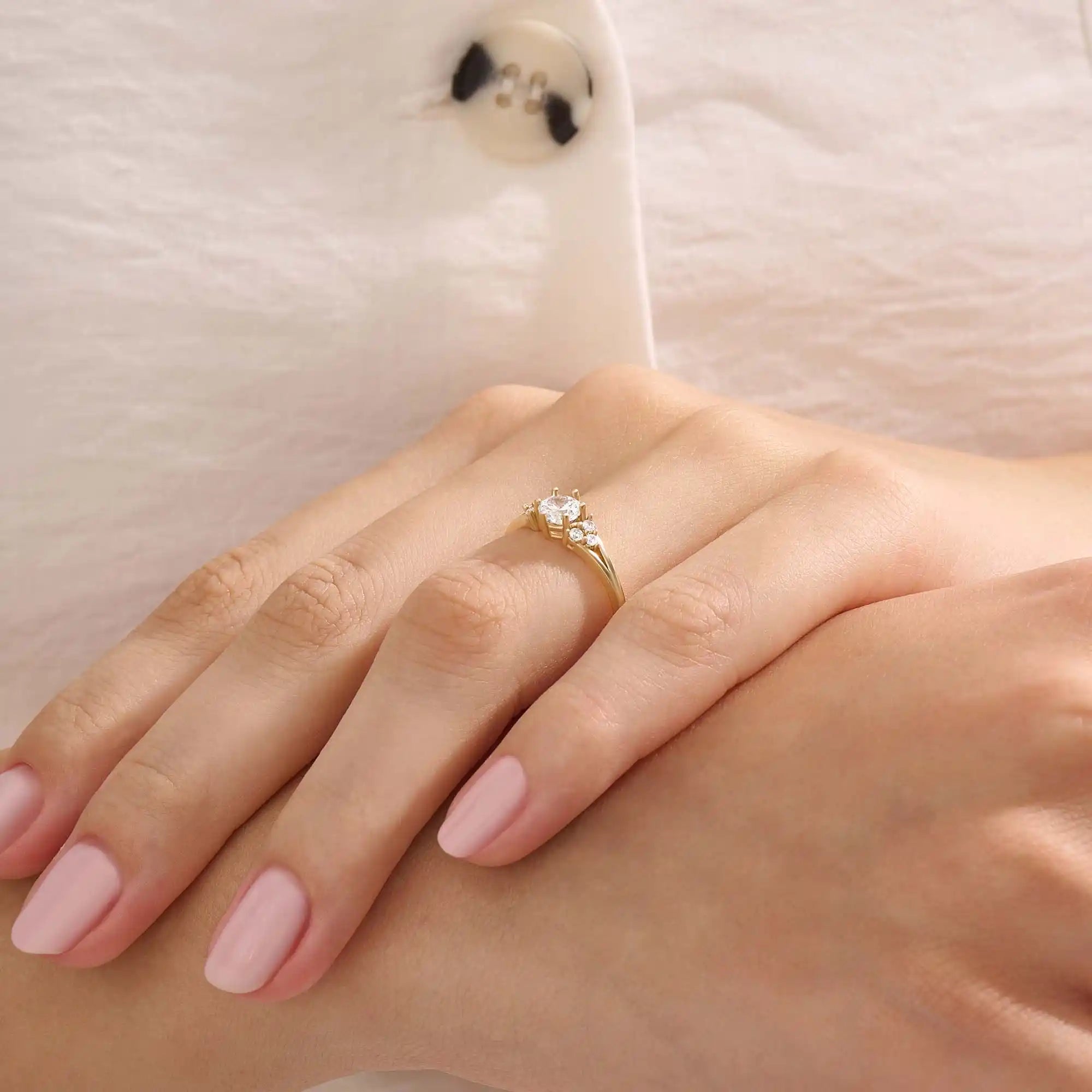 Woman wearing a 14k solid gold engagement ring with a round moissanite and small side accents. A subtle and elegant ring for everyday wear. Ideal for those who love classic, refined style.