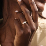Woman wearing a 14k solid gold engagement ring with a round moissanite and small side accents. A subtle and elegant ring for everyday wear. Ideal for those who love classic, refined style.