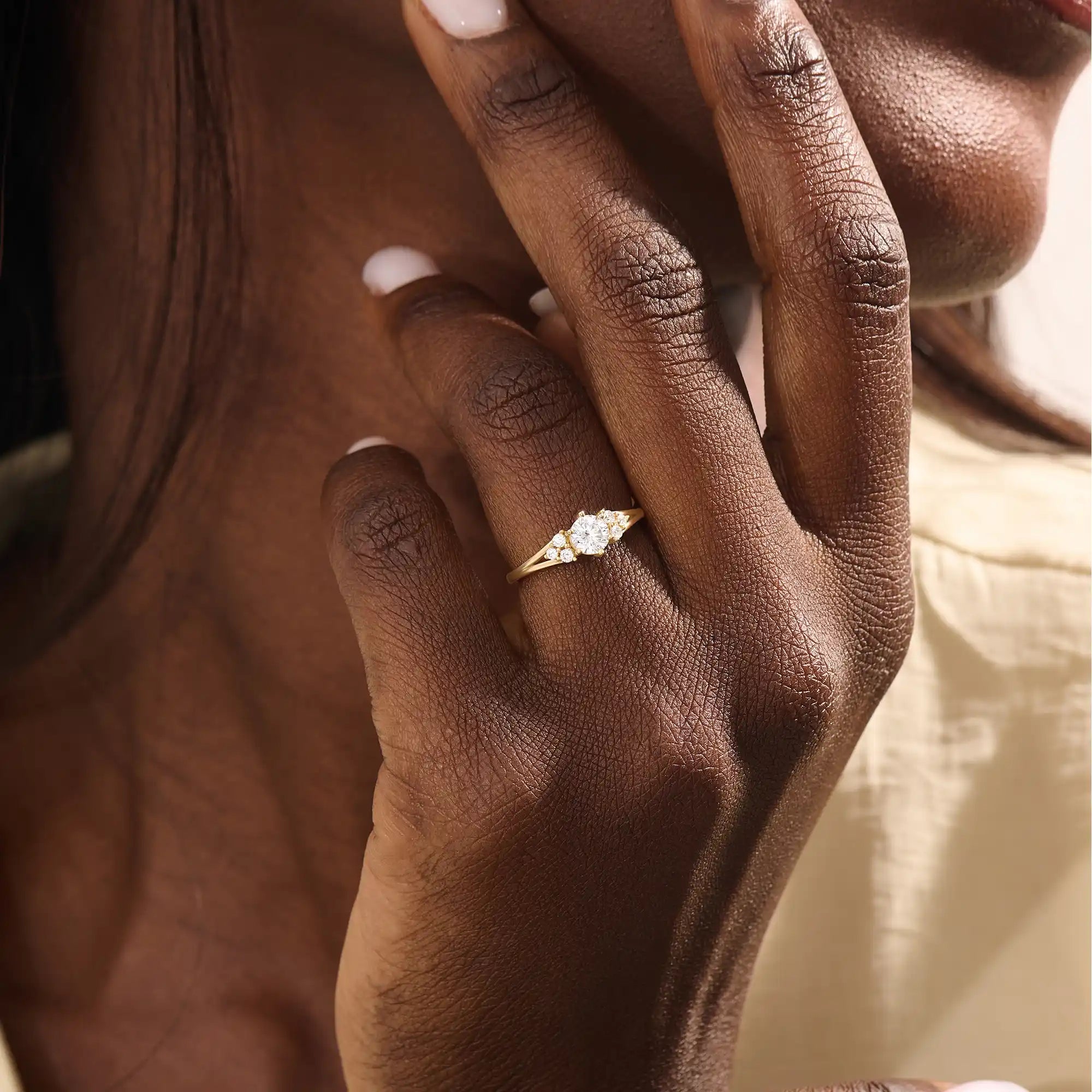 Woman wearing a 14k solid gold engagement ring with a round moissanite and small side accents. A subtle and elegant ring for everyday wear. Ideal for those who love classic, refined style.