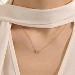 Woman wearing a 14k solid gold evil eye necklace resting at the collarbone. A symbolic and dainty gold design for daily style. Great for layering or wearing solo.