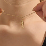 Woman wearing a 14k solid gold fish necklace with a sleek and dainty silhouette. Meaningful and minimalist jewelry piece. Perfect for casual styling or layering.