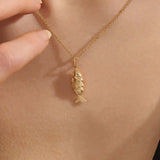 Woman wearing a 14k solid gold fish necklace with a sleek and dainty silhouette. Meaningful and minimalist jewelry piece. Perfect for casual styling or layering.