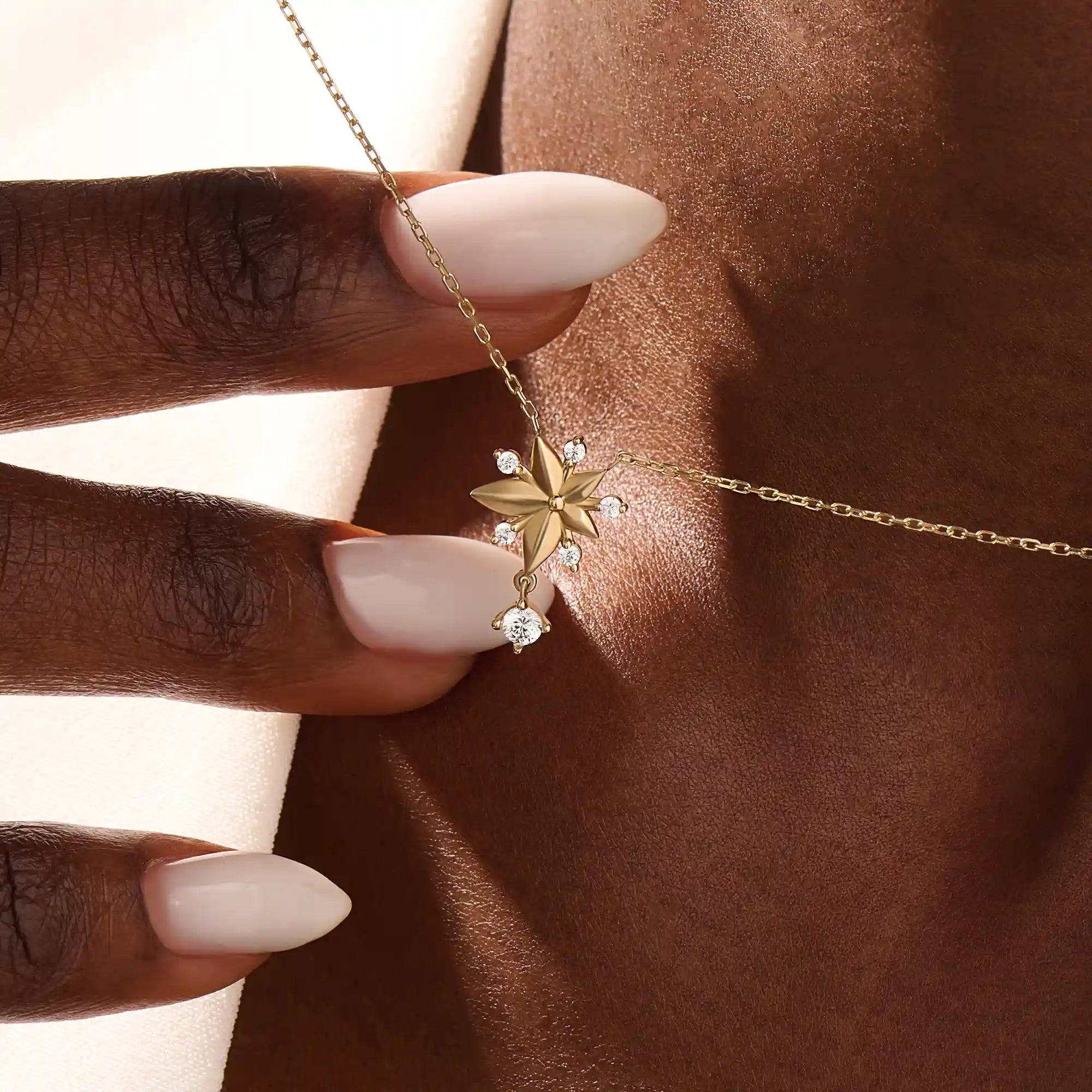 Woman wearing a 14k solid gold flower necklace with five petals and a sparkling dangling moissanite. Nature-inspired and graceful gold jewelry. Perfect for soft, romantic styling.
