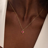 Woman wearing a 14k solid gold heart necklace with a vibrant lab-created ruby. Romantic and timeless gemstone pendant. Perfect for layering or wearing solo.