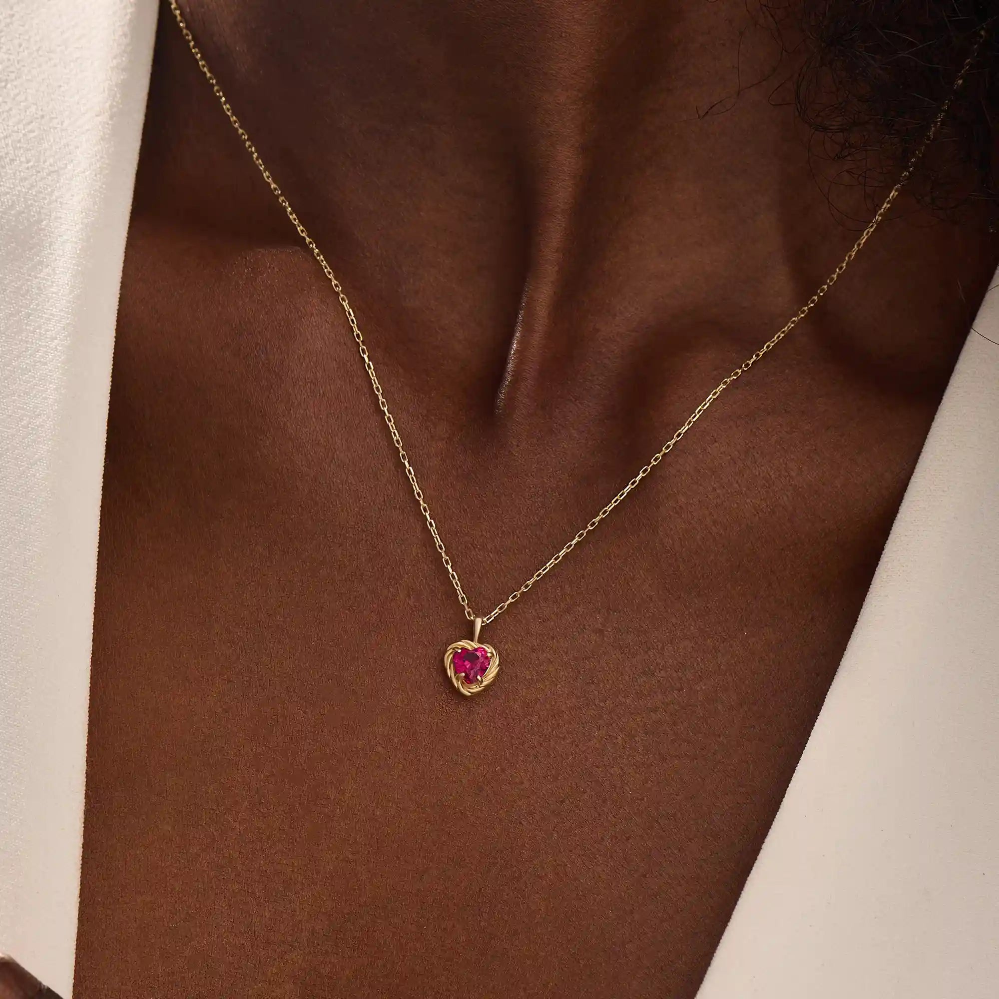 Woman wearing a 14k solid gold heart necklace with a vibrant lab-created ruby. Romantic and timeless gemstone pendant. Perfect for layering or wearing solo.