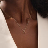 Woman wearing a 14k solid gold heart necklace with a vibrant lab-created ruby. Romantic and timeless gemstone pendant. Perfect for layering or wearing solo.