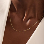 Woman wearing a 14k solid gold mixed metal bar chain necklace with polished yellow and white gold segments. A unique, eye-catching design for daily looks. Great for bold layering or worn alone.