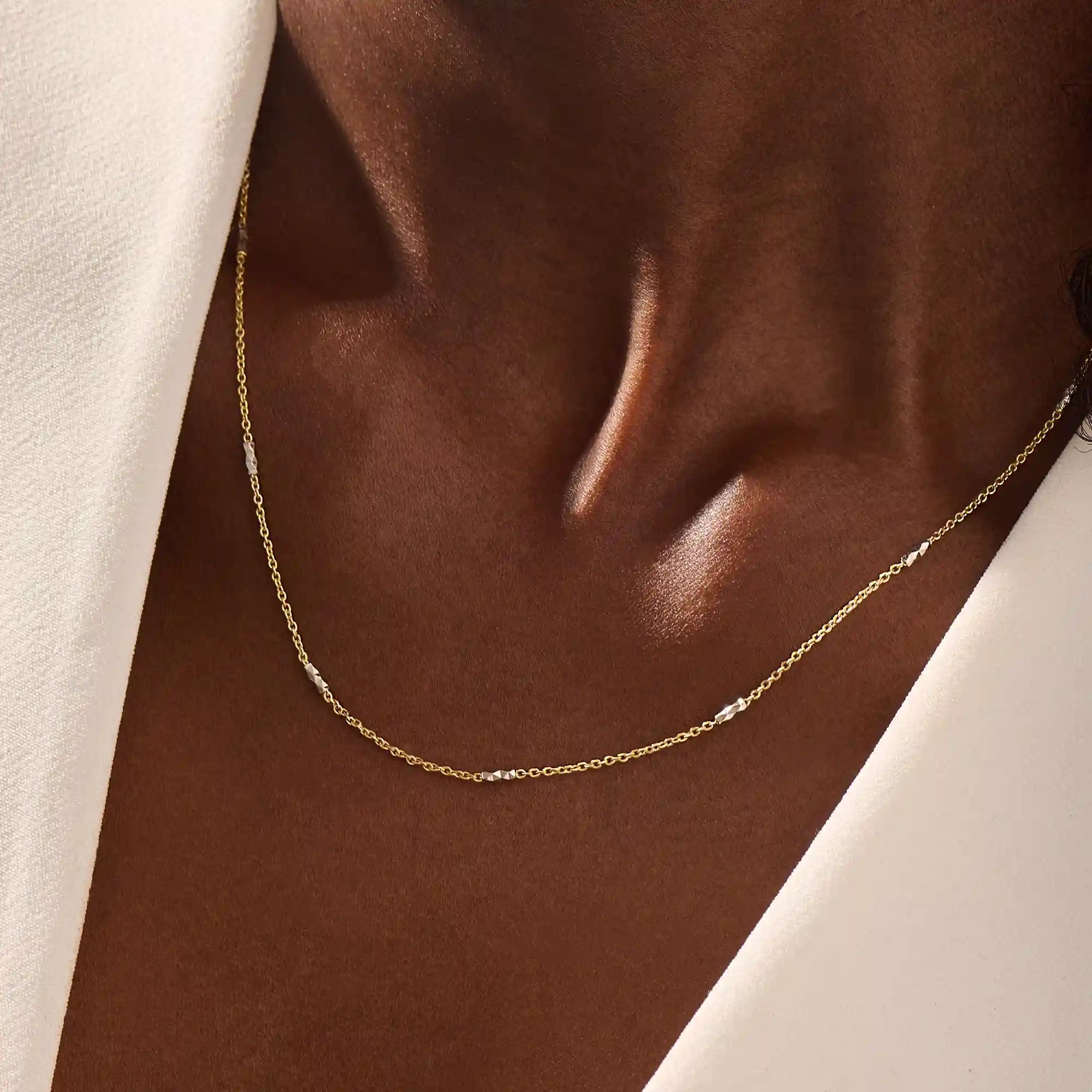 Woman wearing a 14k solid gold mixed metal bar chain necklace with polished yellow and white gold segments. A unique, eye-catching design for daily looks. Great for bold layering or worn alone.