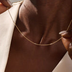 Woman wearing a 14k solid gold mixed metal bar chain necklace with polished yellow and white gold segments. A unique, eye-catching design for daily looks. Great for bold layering or worn alone.