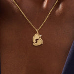 Woman wearing a 14k solid gold necklace with a baby foot pendant and sparkling moissanite detail. A meaningful and dainty gold piece celebrating motherhood and love. Ideal for layering or as a daily keepsake.