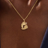 Woman wearing a 14k solid gold necklace with a baby foot pendant and sparkling moissanite detail. A meaningful and dainty gold piece celebrating motherhood and love. Ideal for layering or as a daily keepsake.