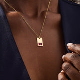 Woman wearing a 14k solid gold rectangle pendant necklace featuring an emerald-cut lab-created ruby in bezel setting. Striking birthstone jewelry with timeless elegance. Ideal for everyday wear or special occasions.