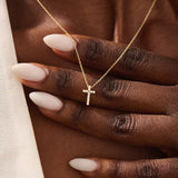 Woman wearing a 14k solid gold reversible cross necklace with pave moissanites on both sides. Subtle and elegant everyday jewelry. Designed for modern layering looks.