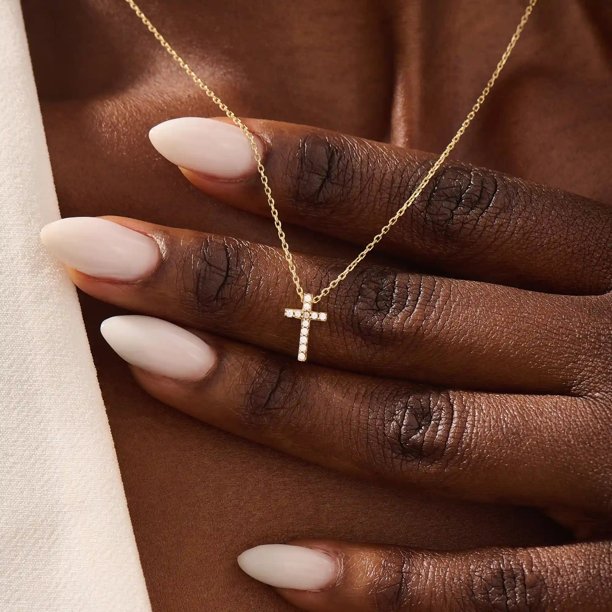 Woman wearing a 14k solid gold reversible cross necklace with pave moissanites on both sides. Subtle and elegant everyday jewelry. Designed for modern layering looks.