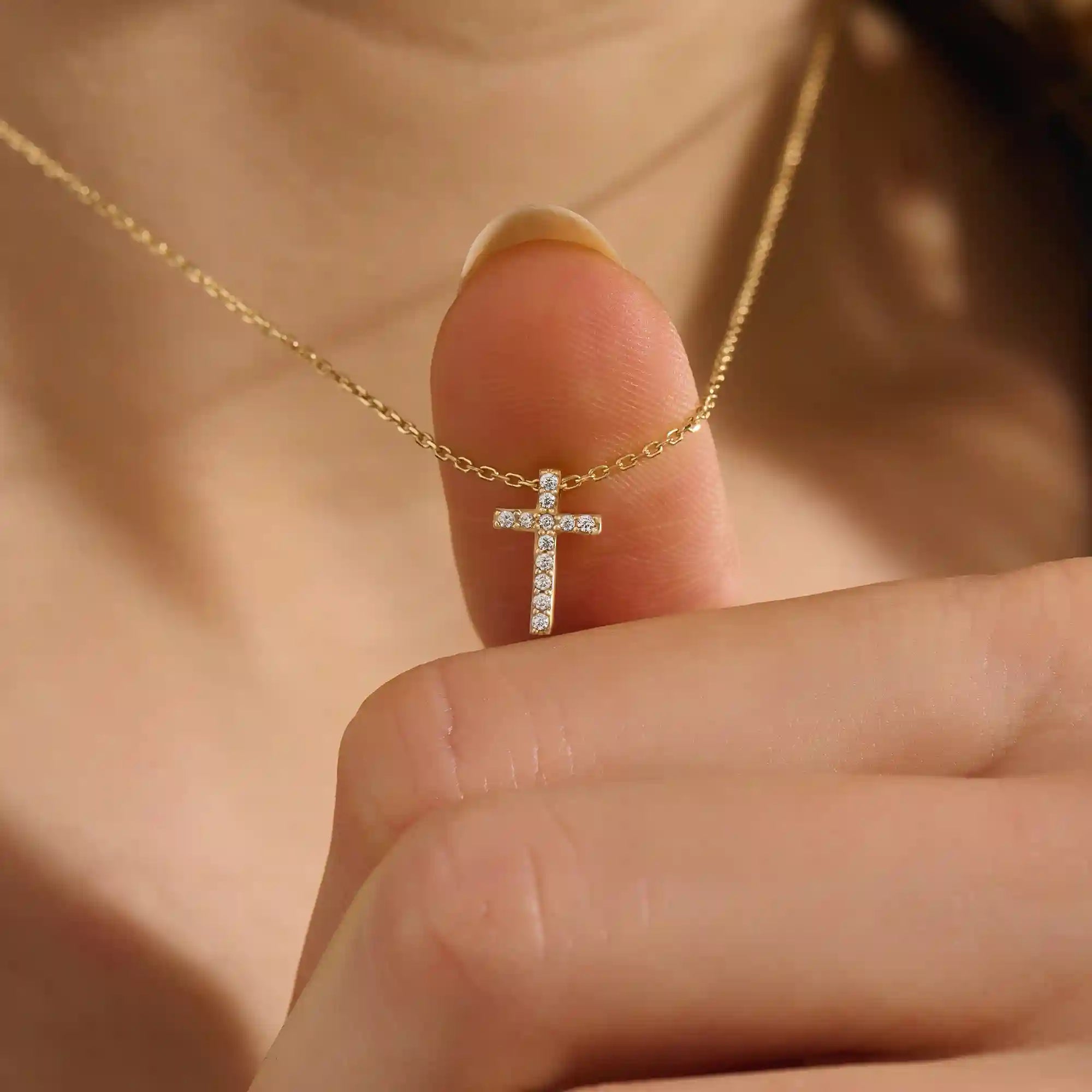 Woman wearing a 14k solid gold reversible cross necklace with pave moissanites on both sides. Subtle and elegant everyday jewelry. Designed for modern layering looks.