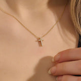 Woman wearing a 14k solid gold reversible cross necklace with pave moissanites on both sides. Subtle and elegant everyday jewelry. Designed for modern layering looks.