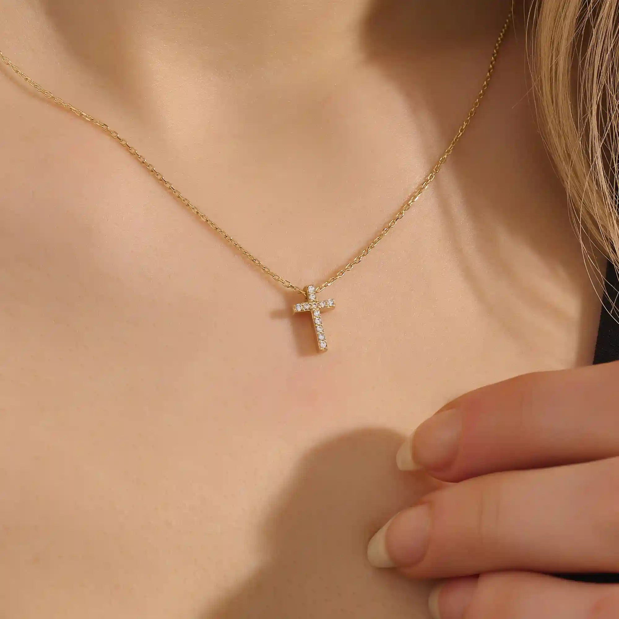 Woman wearing a 14k solid gold reversible cross necklace with pave moissanites on both sides. Subtle and elegant everyday jewelry. Designed for modern layering looks.