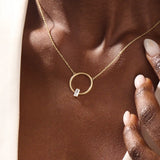 Woman wearing a 14k solid gold round karma necklace featuring a baguette moissanite in the center. Bold yet dainty gold design. Perfect for meaningful daily layering.