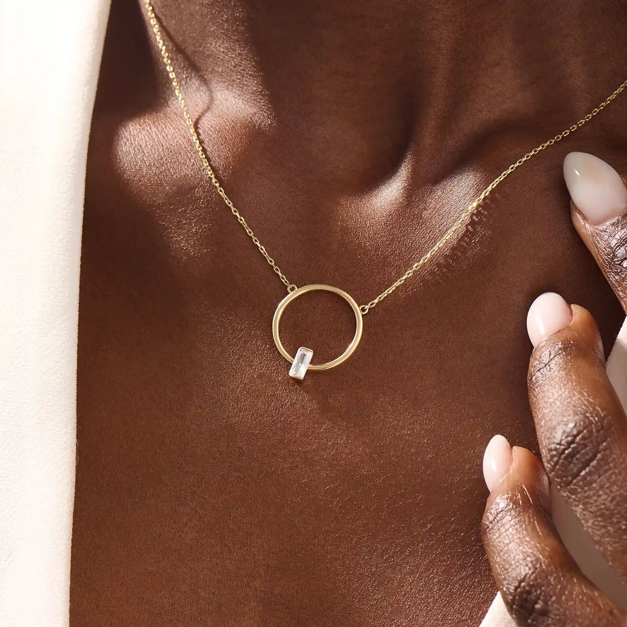 Woman wearing a 14k solid gold round karma necklace featuring a baguette moissanite in the center. Bold yet dainty gold design. Perfect for meaningful daily layering.