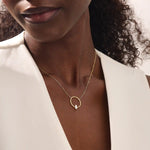Woman wearing a 14k solid gold round karma necklace featuring a baguette moissanite in the center. Bold yet dainty gold design. Perfect for meaningful daily layering.