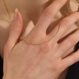 Woman wearing a 14k solid gold slim Figaro chain necklace with a delicate, timeless link pattern. Subtle and elegant for everyday styling. Great on its own or stacked.